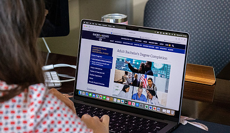 Woman using a computer with the Adult Bachelor's Degree Completion program website on the screen