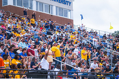 An audience cheering on the E&H football team from the bleachers