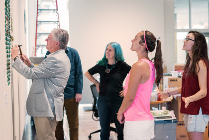 Students work with visiting artists, including during the installation process.  Here students, and even President Jake Schrum, work with...