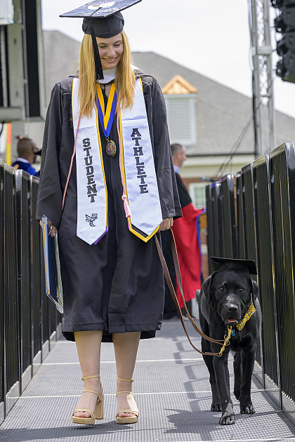 Graduate walking down stage with dog