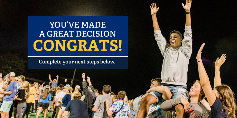 A group of students hold up a student with their hands up high in the air