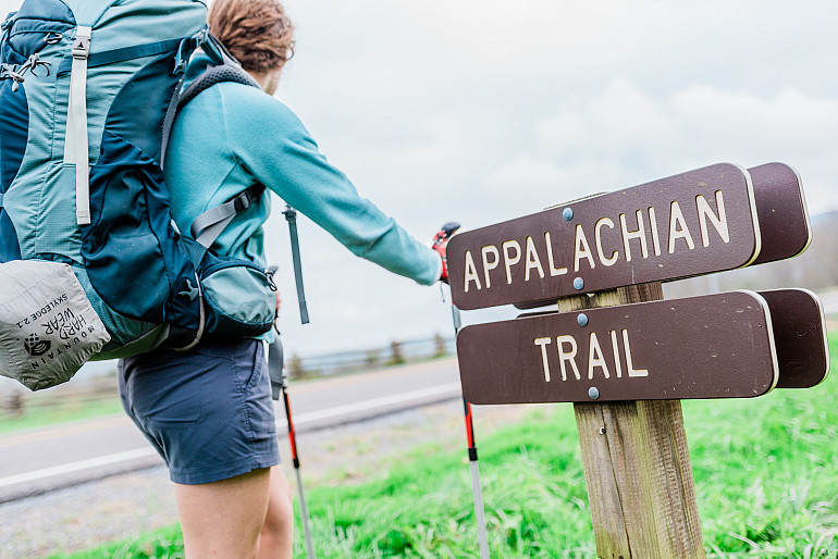 A student hiker and a trail marker inscribed with the text Appalachian Trail