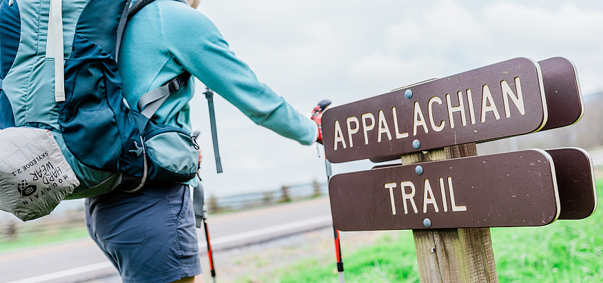 A student hiker and a trail marker inscribed with the text Appalachian Trail