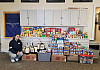 A person posing with donated food drive items